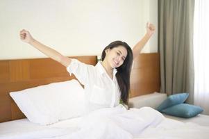 una mujer sonriente estirando las manos después de despertarse por la mañana en casa. foto