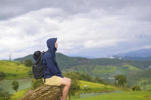 hombre viajero disfrutando y relajándose sobre la hermosa vista verde de la montaña en temporada de lluvia, clima tropical.