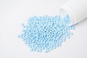 Montones de pastillas azules sobre fondo blanco.