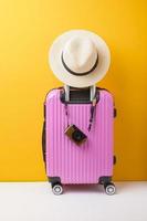 equipaje rosa sobre fondo amarillo, concepto de viaje foto