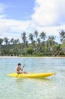un joven deportista haciendo kayak en el océano en un día soleado foto