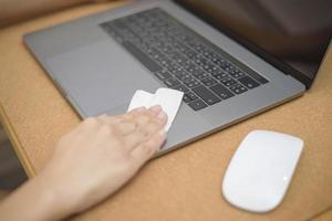 la mujer está limpiando la computadora portátil con spray de alcohol foto