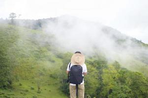 Traveling man enjoying and relaxing over beautiful green mountain view in rain season, Tropical climate.