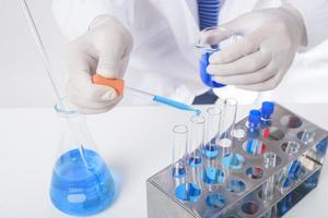 close up of cientist is testing and researching some blue liquid chemical in laboratory isolated white background. photo