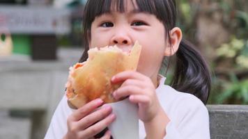 Adorable little girl enjoy eating crepe  with jelly and chocolate sauce in the park. Summer bright and delicious breakfast, dessert or snack.