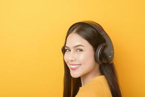 Music lover woman is enjoying with headset on yellow background photo