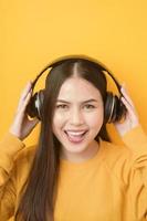 la mujer amante de la música está disfrutando con auriculares con fondo amarillo foto