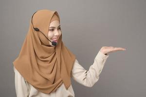 retrato de una hermosa mujer del centro de llamadas con hiyab sobre fondo gris foto