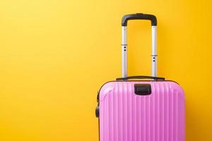 equipaje rosa sobre fondo amarillo, concepto de viaje foto