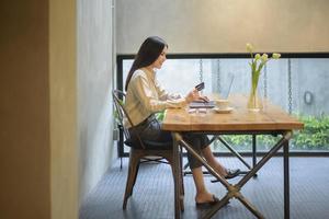 Beautiful woman is online shopping with credit card in coffee shop photo