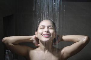 mujer hermosa joven duchándose en un baño en casa foto