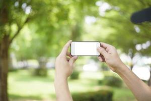 A man is holding cell phone on green photo