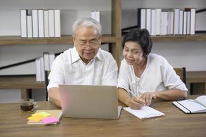 A happy senior Asian couple is spending time on surfing  the internet and talking with family on webcam,  retirement concept. photo
