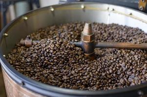 los granos de café se asan en una máquina tostadora en una cafetería. foto