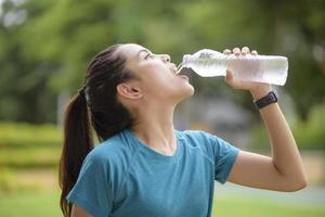 mujer fitness está bebiendo agua después de hacer ejercicio en el parque