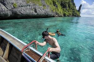 un hombre activo en un bote de cola larga tradicional tailandés está listo para bucear y bucear, islas phi phi, tailandia foto