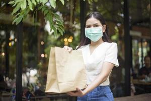 hermosa mujer está recibiendo una bolsa de comestibles en casa, concepto de entrega a domicilio de seguridad foto