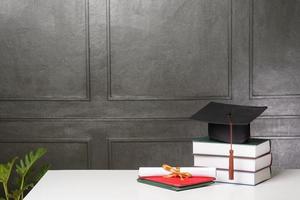 gorra de graduación con libros en escritorio blanco, antecedentes educativos foto