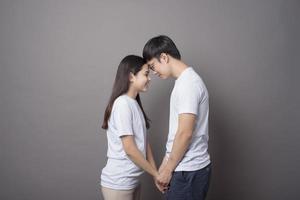 a portriat of a happy couple wearing blue shirt is hugging each other in grey background studio photo