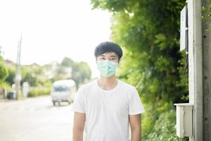 joven asiático lleva mascarilla en la ciudad al aire libre foto