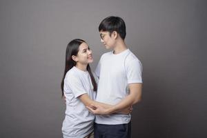 a portriat of a happy couple wearing blue shirt is hugging each other in grey background studio photo