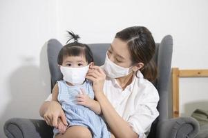 Mom and daughter are wearing protective mask , safety in home , covid-19 protection , healthy at home concept photo