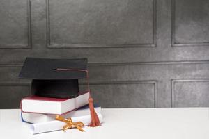 gorra de graduación con libros en escritorio blanco, antecedentes educativos foto