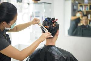 un joven se está cortando el pelo en una peluquería, concepto de seguridad en el salón foto