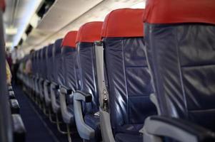 una cabina de avión con filas de asientos de pasajeros vacías. foto