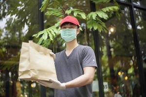 An Asian delivery man is wearing face mask, holding grocery bag , Safety home delivery concept photo