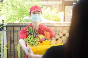 The courier man in protective mask and gloves is deliver box food during virus outbreak. Safe home delivery. photo