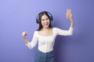 Young woman is listening to music  on purple background photo