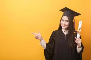 retrato de una mujer feliz y hermosa con un vestido de graduación tiene un certificado de educación con antecedentes amarillos foto