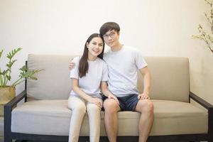 a happy couple wearing blue shirt is sitting on a sofa at home photo