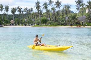 un joven deportista haciendo kayak en el océano en un día soleado foto