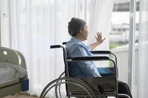 Depressed and hopeless Asian cancer patient woman wearing head scarf in hospital. photo