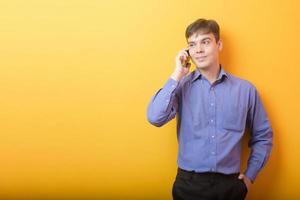portrait of young business man is using a smart phone on yellow background studio photo