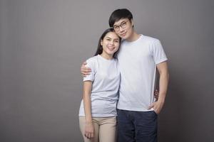 a portriat of a happy couple wearing blue shirt is hugging each other in grey background studio photo