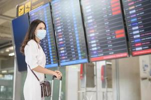 una mujer viajera lleva una máscara protectora en el aeropuerto internacional, viaja bajo la pandemia de covid-19, viajes de seguridad, protocolo de distanciamiento social, nuevo concepto de viaje normal