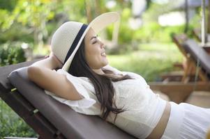 A young woman relaxing and sitting on the lounge chair looking at beautiful beach on holidays photo