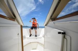 tourist in life jacket enjoying and relaxing on speedboat with a beautiful view of ocean and mountain in backgound photo