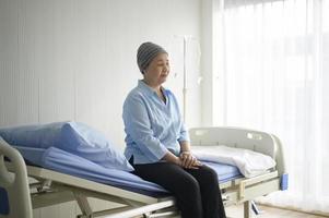Depressed and hopeless Asian cancer patient woman wearing head scarf in hospital. photo