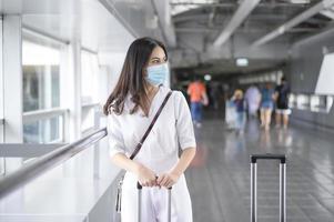 una mujer viajera lleva una máscara protectora en el aeropuerto internacional, viaja bajo la pandemia de covid-19, viajes de seguridad, protocolo de distanciamiento social, nuevo concepto de viaje normal