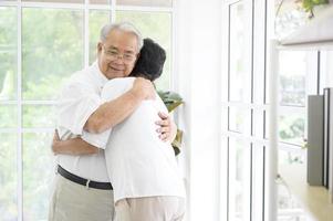 A senior elderly couple are hugging in home photo