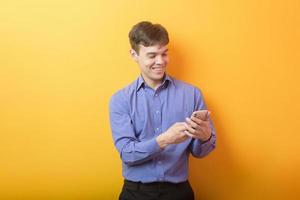 portrait of young business man is using a smart phone on yellow background studio photo