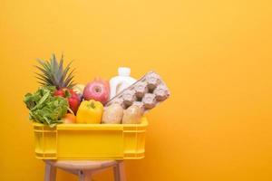 Set of delivery raw food in plastic box on yellow  background photo