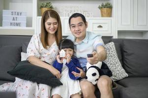 una familia asiática feliz viendo la televisión pasa tiempo juntos en casa los fines de semana foto