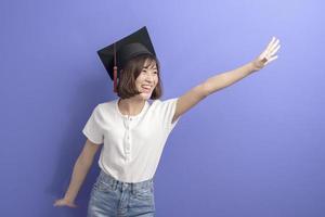 Portrait of young Asian student wearing graduation cap over studio background. photo