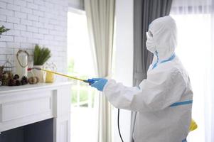 un personal médico con traje de ppe está usando spray desinfectante en la sala de estar, protección covid-19, concepto de desinfección. foto