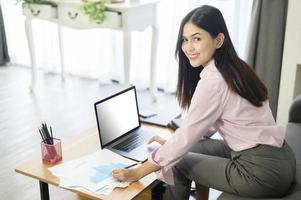 una mujer de negocios está trabajando con una pantalla simulada de una computadora portátil, analizando el plan de negocios en la oficina del hogar. foto